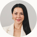 Woman with long dark hair and a white blazer on a gray background