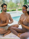 Two people meditating by a pool with headphones on