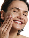 Woman applying product to her face with a white background