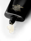 Cleansing balm bottle with product coming out of it on a light background