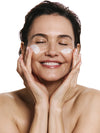 Woman applying product to her face with both hands against a white background