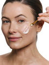 Woman applying cream on her face with a applicator