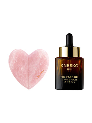 Knesko face oil bottle with a heart-shaped pink gua sha on a white background