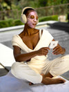 Woman masking and meditating, holding a KNESKO meditation card with headphones