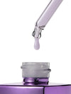 A close-up studio shot of a purple cosmetic dropper above an open purple bottle, with a single clear droplet hanging in the center against a white background.