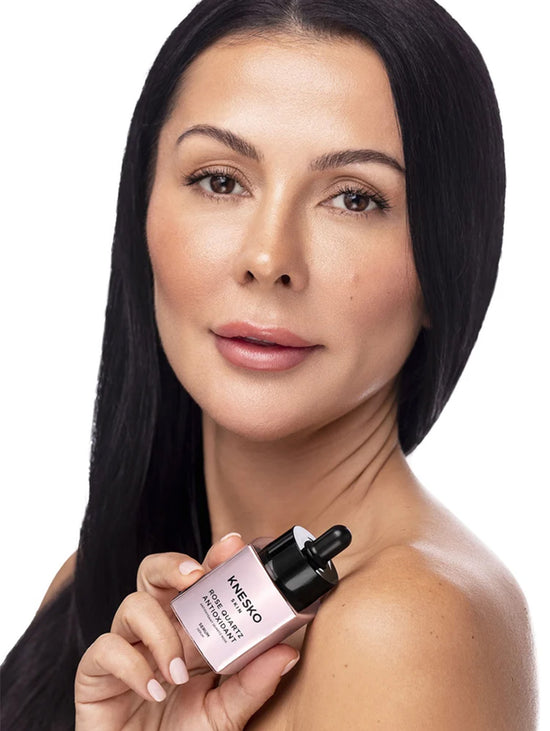 A woman with long black hair holds an Avene Hyaluve White-Celadon Serum bottle against a clean white background.