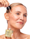 Woman applying Knesko skincare product to her face with a dropper.