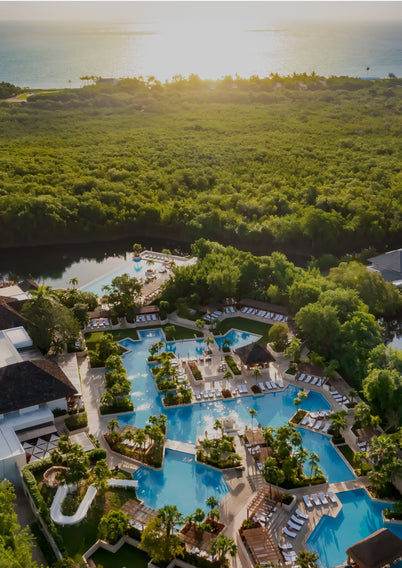 Aerial view of a luxurious resort with multiple pools and spa areas surrounded by lush greenery.