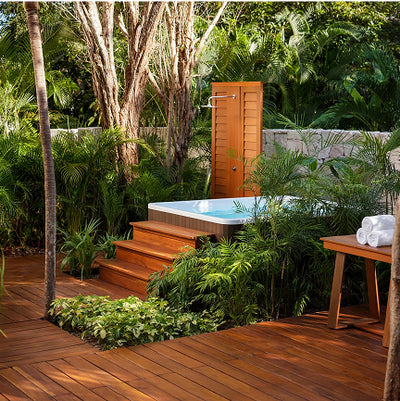 Outdoor hot tub surrounded by lush greenery and wooden deck