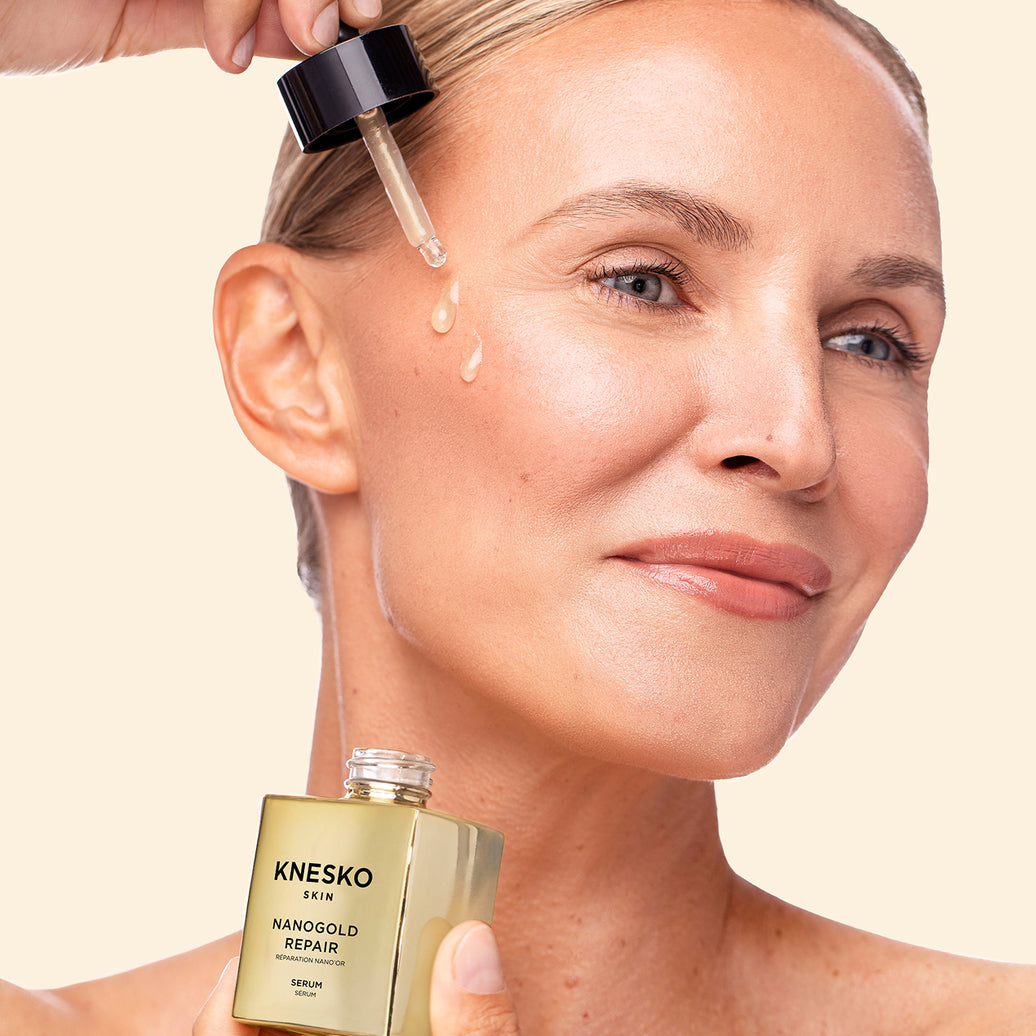Woman applying Knesko serum to her face with a dropper.