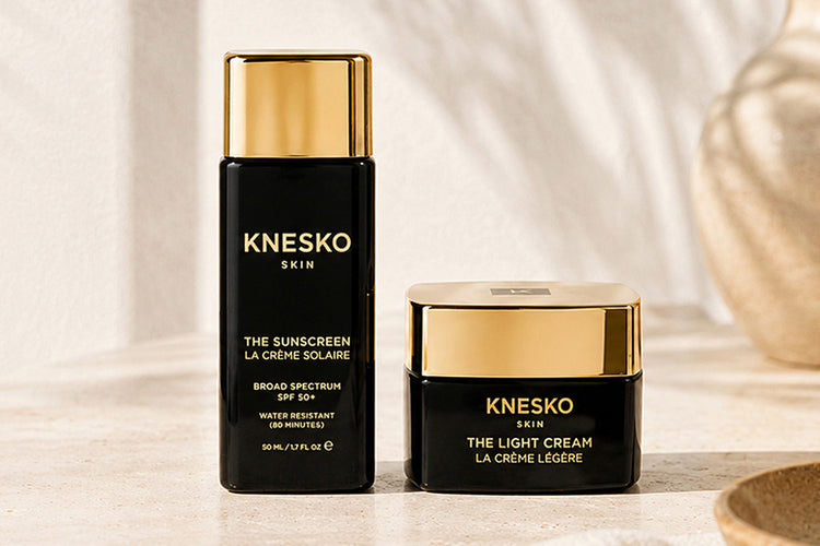 Knesko Skin skincare set featuring The Sunscreen and The Light Cream, displayed on a light stone surface.