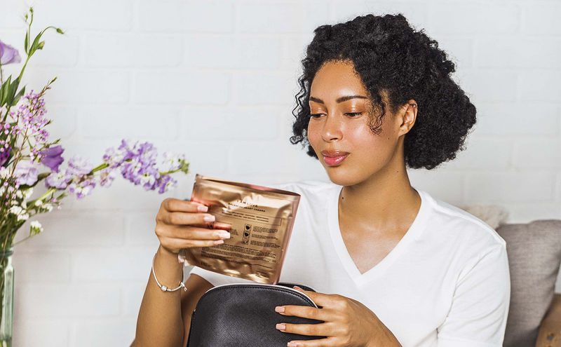 Woman holding a bronze-colored product with flowers in the background