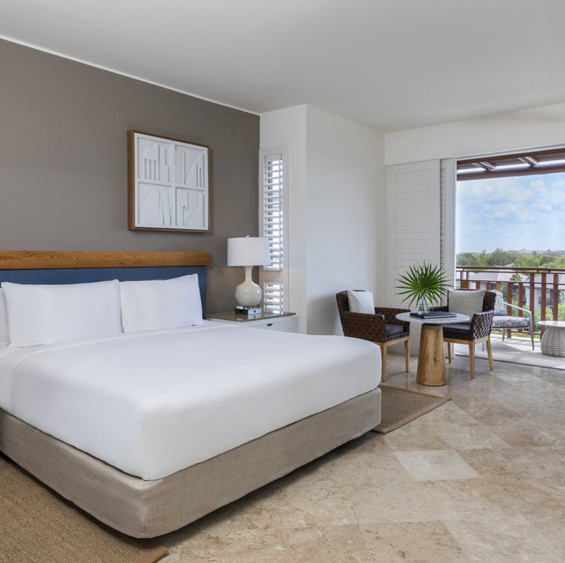 Modern bedroom with a large bed, lamp, and view of a balcony.