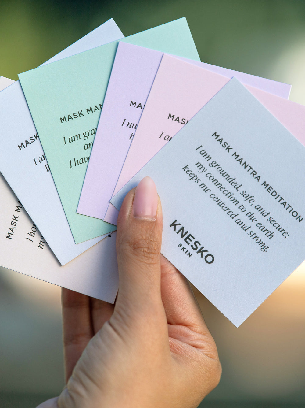 Hand holding KNESKO meditation cards on blurred background