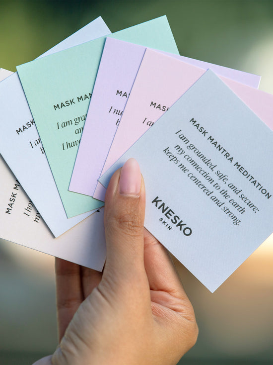 Hand holding KNESKO meditation cards on blurred background