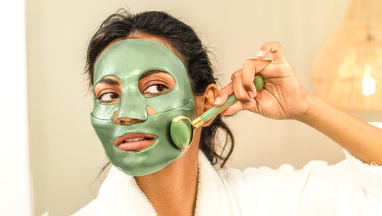 Woman applying green face mask with roller to her face