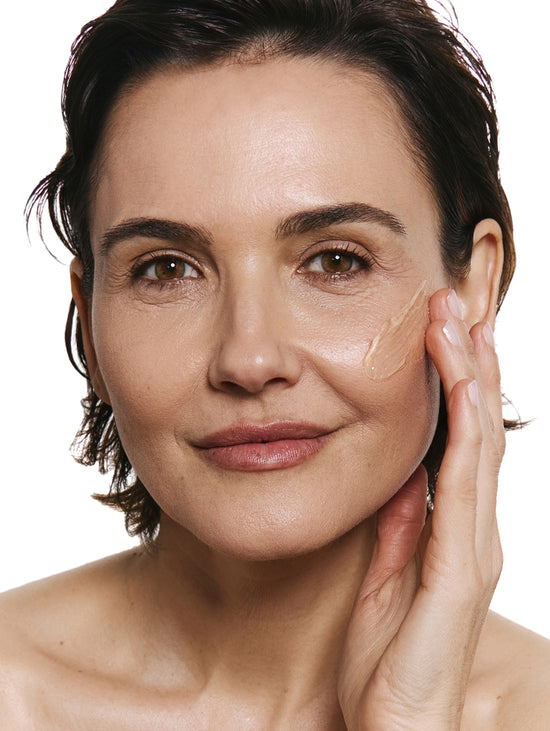 Woman applying product on her face on a white background